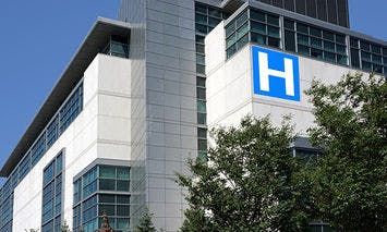 A multi-story hospital building, identifiable by a large blue 